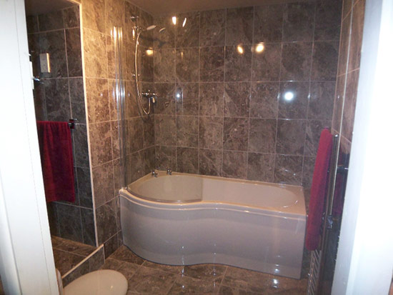 Slate style tiles bathroom with curved bath
